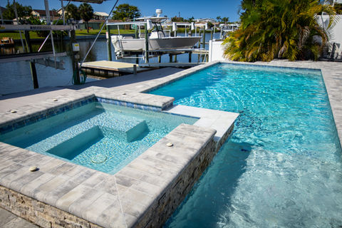 Stone and concrete pool and jacuzzi near boat dock designed and built by Trinity Pools in Florida