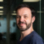 A photo of Richard Banks: a portrait of a white man with dark hair and a beard, standing in an office environment