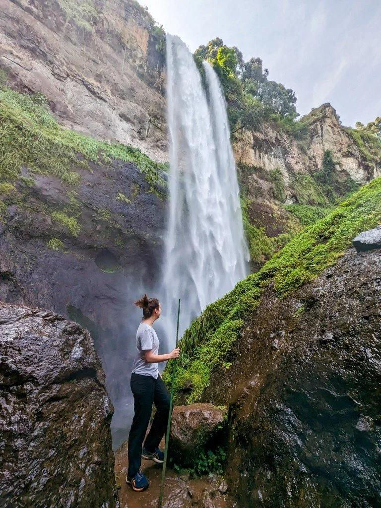 Hiker viewing a towering waterfall at Sipi Falls.