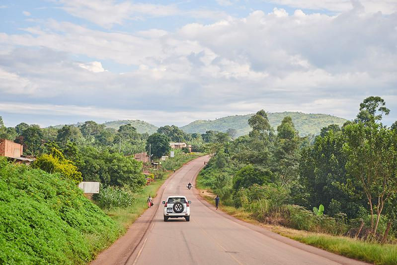 Car driving on a road toward Fort Portal, Uganda Tour