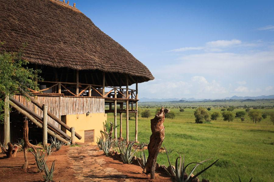 Thatched safari lodge overlooking a scenic Uganda tour landscape.