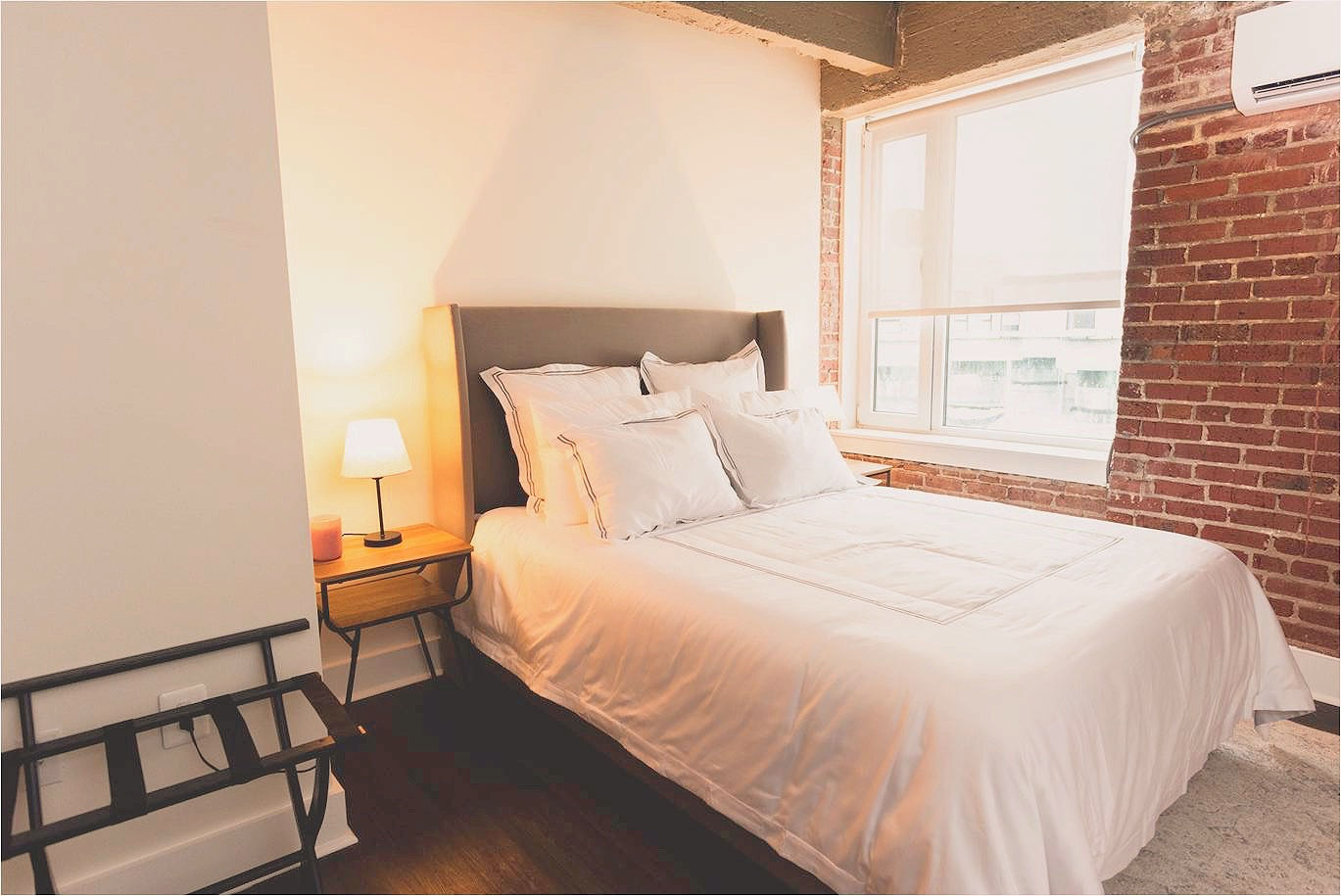 Bedroom with exposed brick walls, a queen size bed, and modern nightstand
