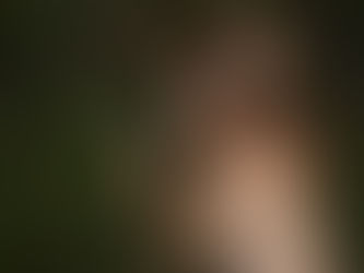 Vrouw liggend in het gras, hand in het haar, ogen gesloten — overgave en rust in het lichaam.