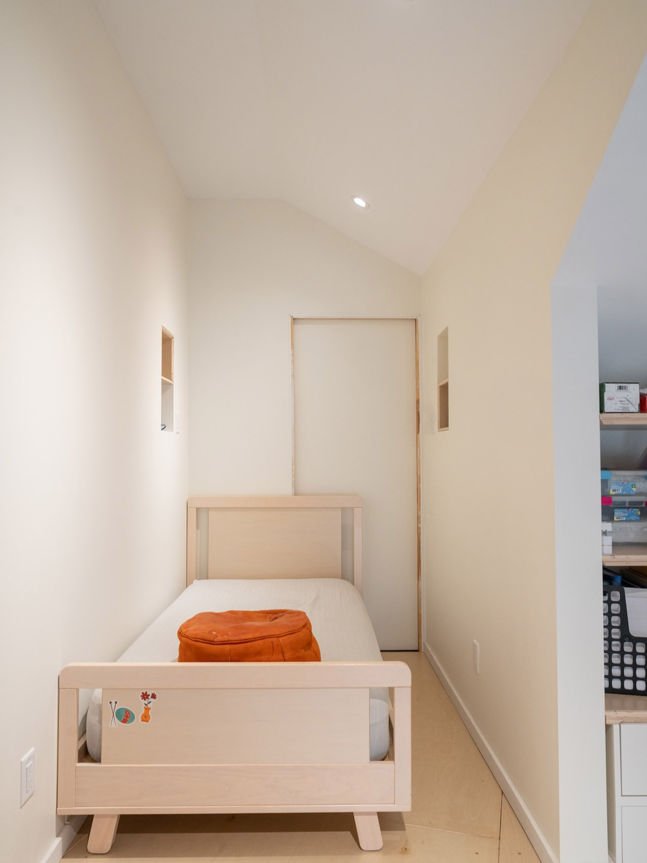 Minimalist bedroom in the attic with white walls, a single bed, and soft lighting creating a calm atmosphere