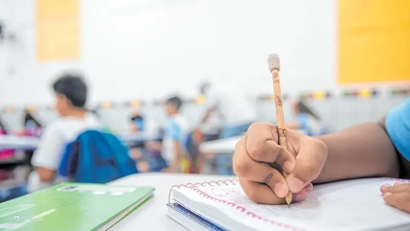 Mão de uma criança escrevendo em um caderno escolar