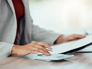 Mulher usando calculadora e escrevendo em papel