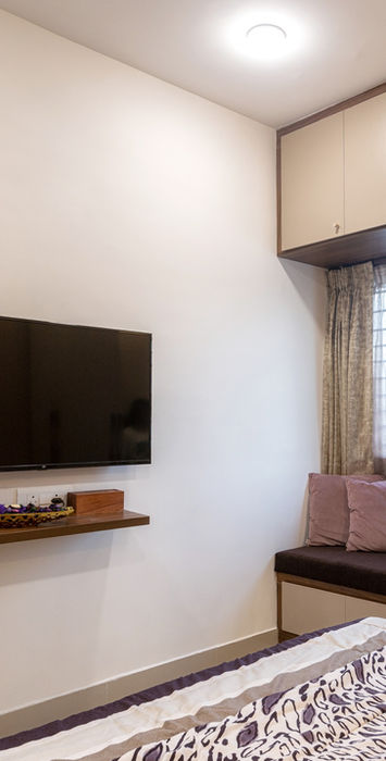 Bedroom with wall-mounted TV, window seating, and storage cabinets