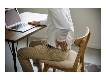 'Office worker holding lower back in pain at desk — lower back pain treatment at Well By Design Chiropractic Balwyn North'