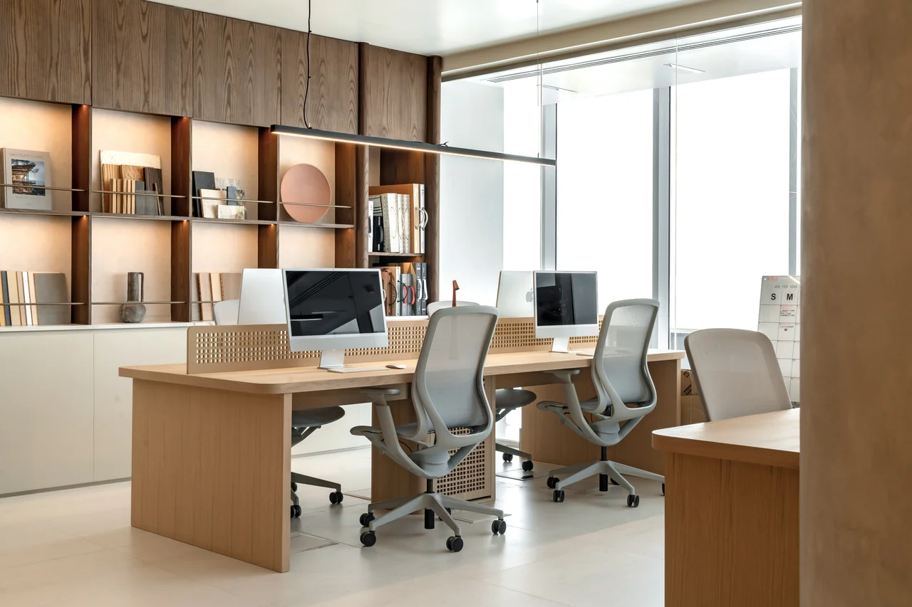 Shared desks and ergonomic chairs beside large windows in C’est ici Design’s own studio.