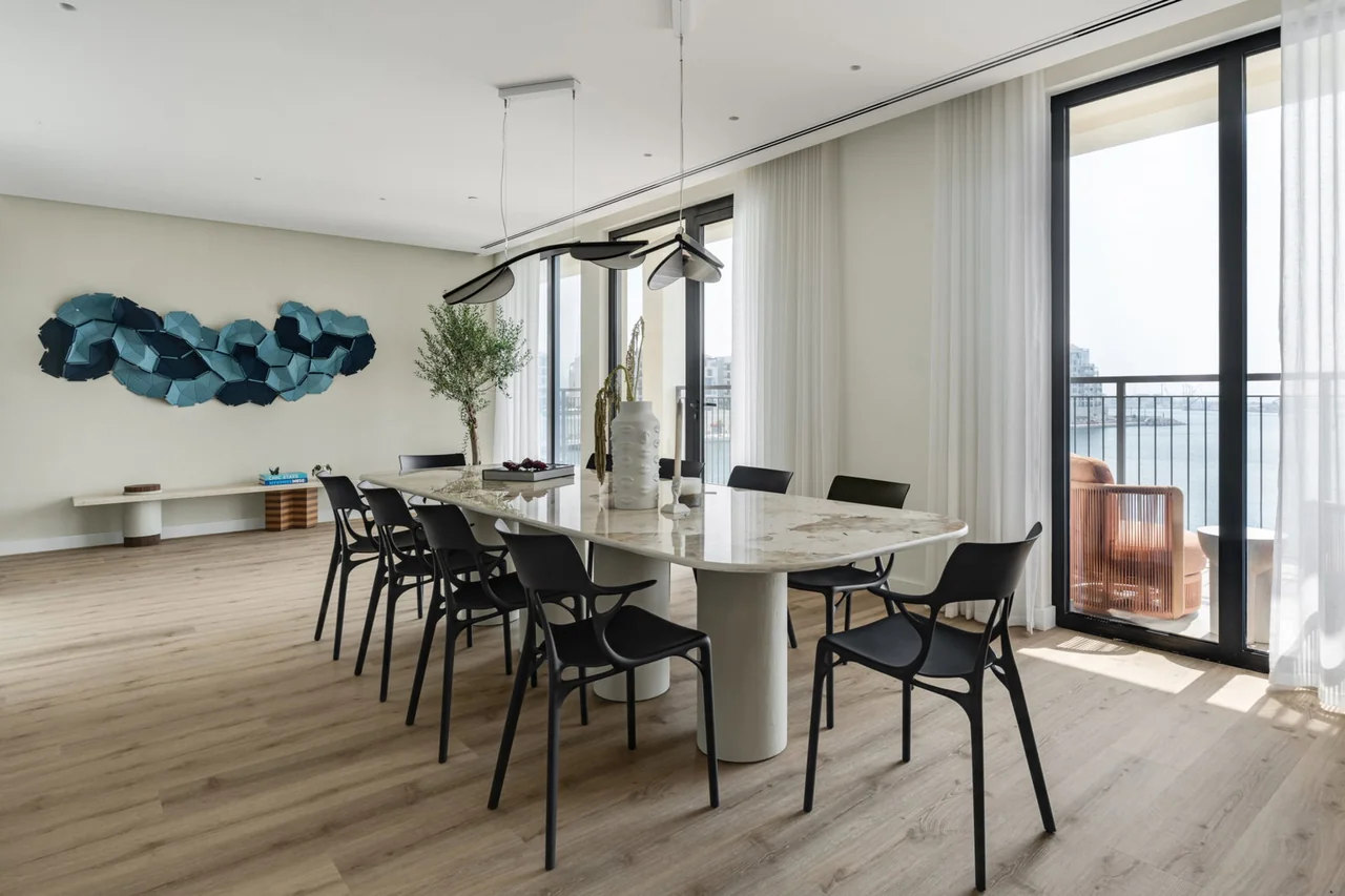 Montenegro apartment dining area with a stone table, black chairs and full-height windows overlooking the coast.