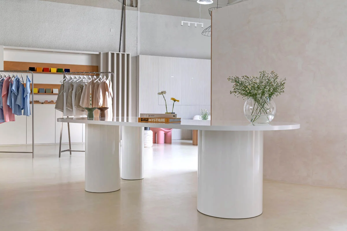 KAGE boutique with curved pale display counters, a textured partition and clothing rails.