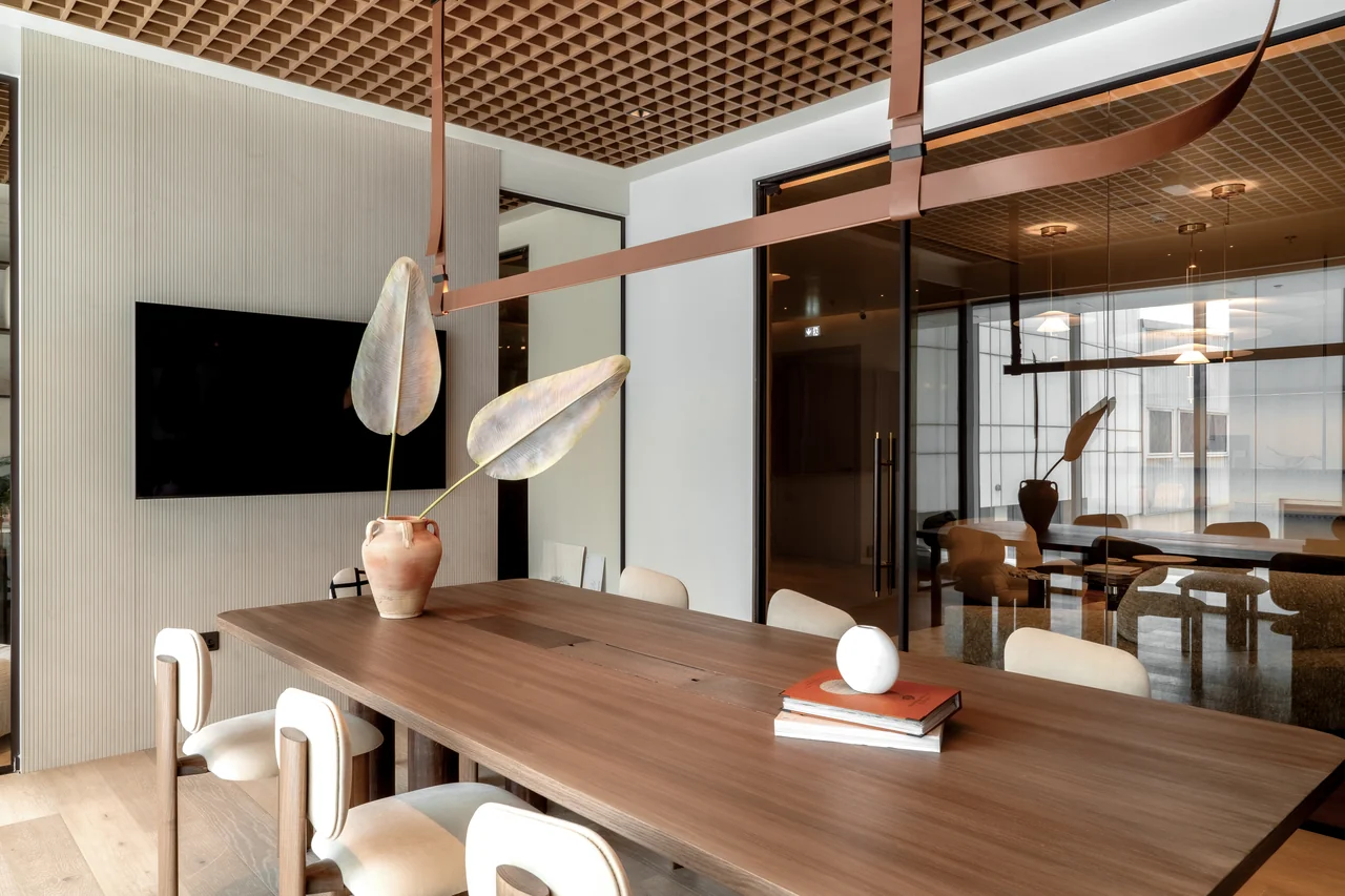 Timber meeting table with upholstered chairs, sculptural lighting and glazed partitions in Studio 2.0.