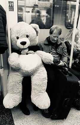 Person carrying a huge teddy bear in the tube
