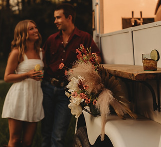 Smiling couple with drinks at a mobile wedding bar trailer