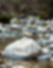 Serene creek background, with a small round balanced rock tower, rocks are different color