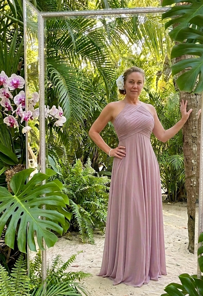 Woman in long mauve dress, flowers in hair, tropical garden