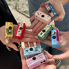 Collection of YASHICA FUNtastic Keychain Cameras in pink, blue, green, yellow and red, held in hands