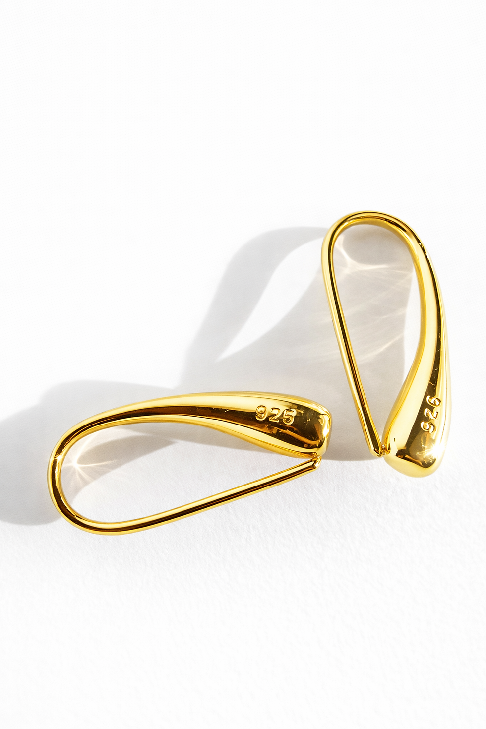 Minimalist gold ear hooks with a smooth teardrop shape, stamped 925 sterling silver, displayed on a white background.