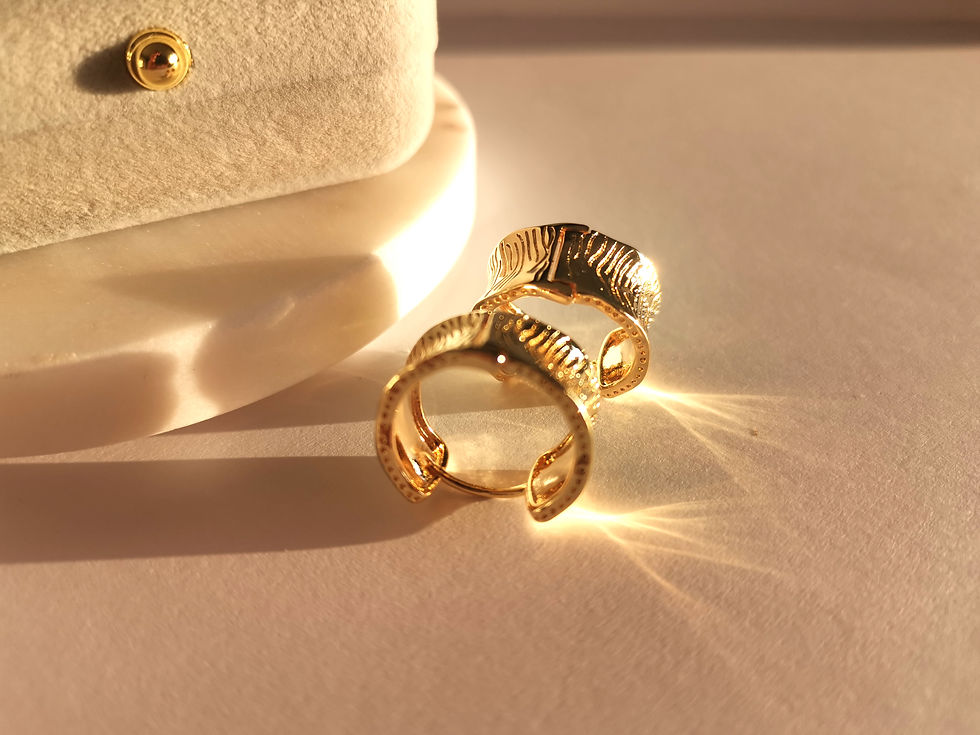 Textured gold hoop earrings with a bold sculptural design and high-polish finish on a soft neutral background.