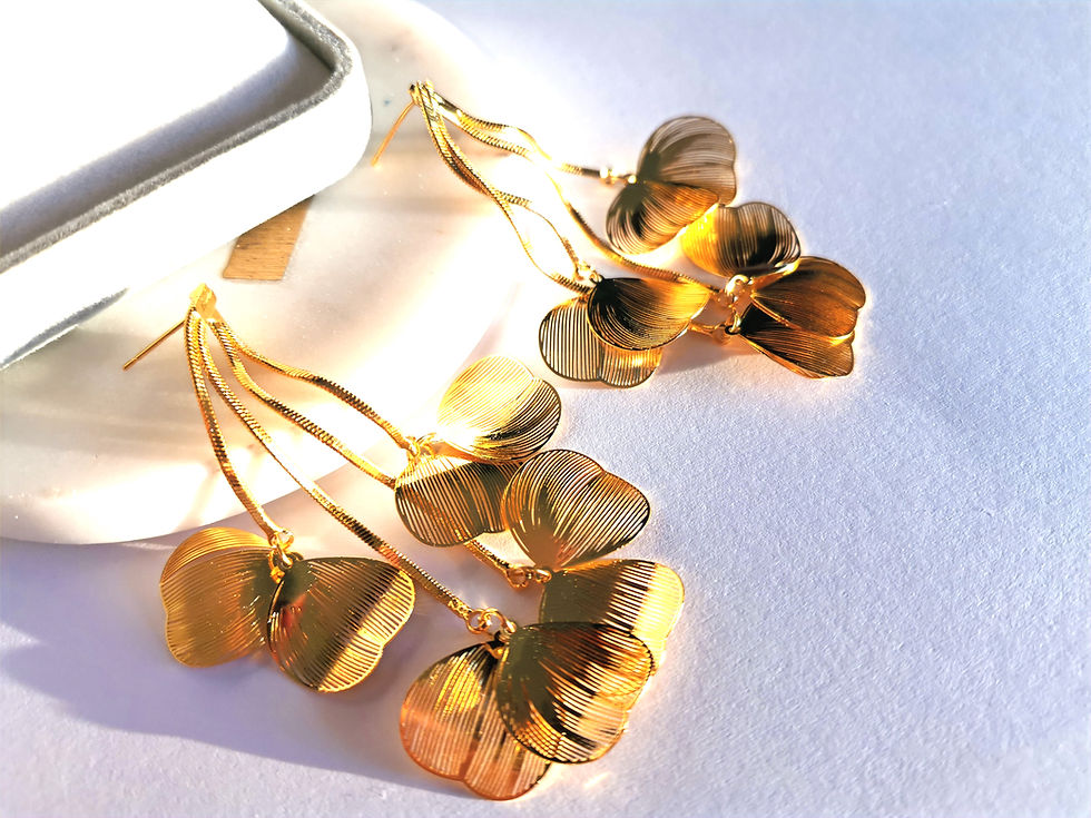 Gold floral dangle earrings with layered petal charms and snake chain details on a white background