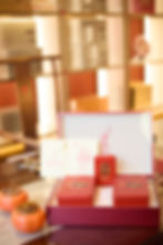 Red Chinese tea gift box with geometric pattern and Sea Dyke brand label, displayed beside two ceramic tea jars on a reflecti