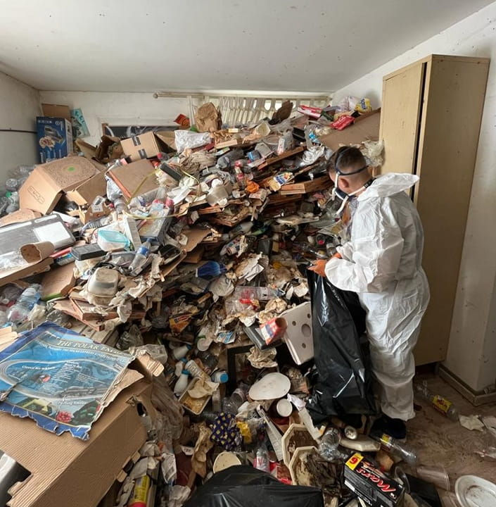 Technicien Maisoneuf remplissant des sacs déchets lors d’un débarras Diogène dans une maison fortement encombrée