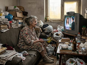 Femme atteinte du syndrome de Diogène assise sur un canapé dans un logement encombré et insalubre entouré de déchets et d’objets accumulés