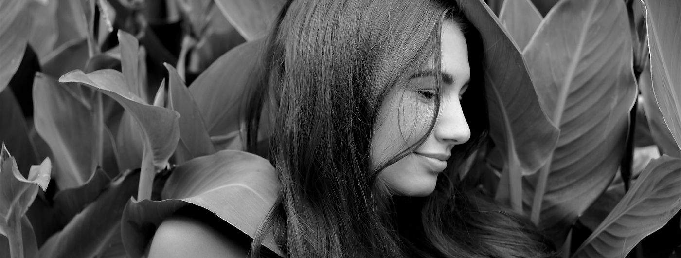 black and white portrait of a young woman against beautiful greenery