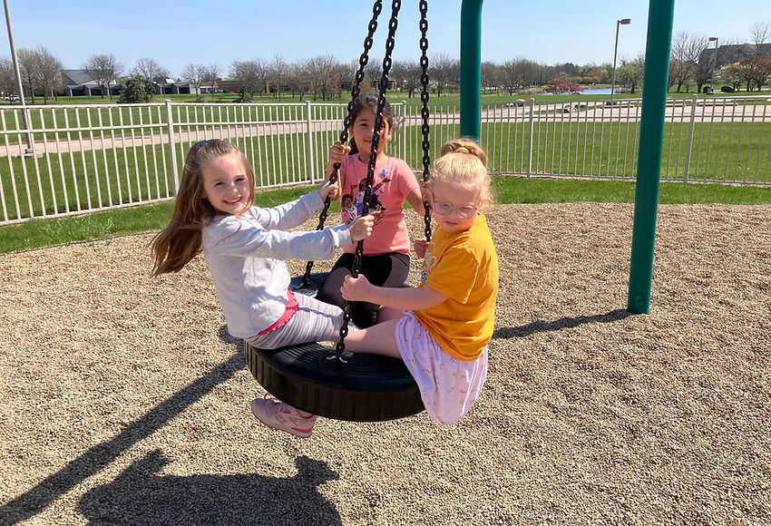 Three girls enjoy a playground tire swing