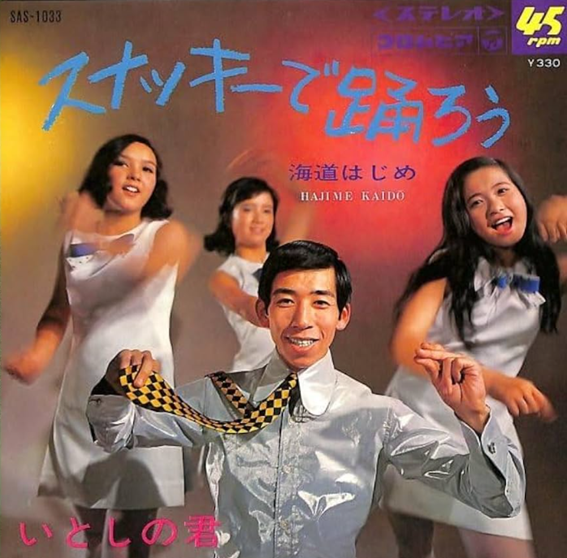 意味不明なジャケットに注目。決して酔ったサラリーマンではない。ゴーゴーダンスをするスナッキーガールズ。海道はじめの左手がスナッキーサイン、右手でつまんだネクタイの柄がプリマハムの新商品スナッキーのパッケージと同じ模様。レコードジャケットに戦略を詰め込みすぎて、おバカな絵面になってしまったのだ。