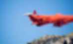 Airplane dropping fire retardant on a forest fire