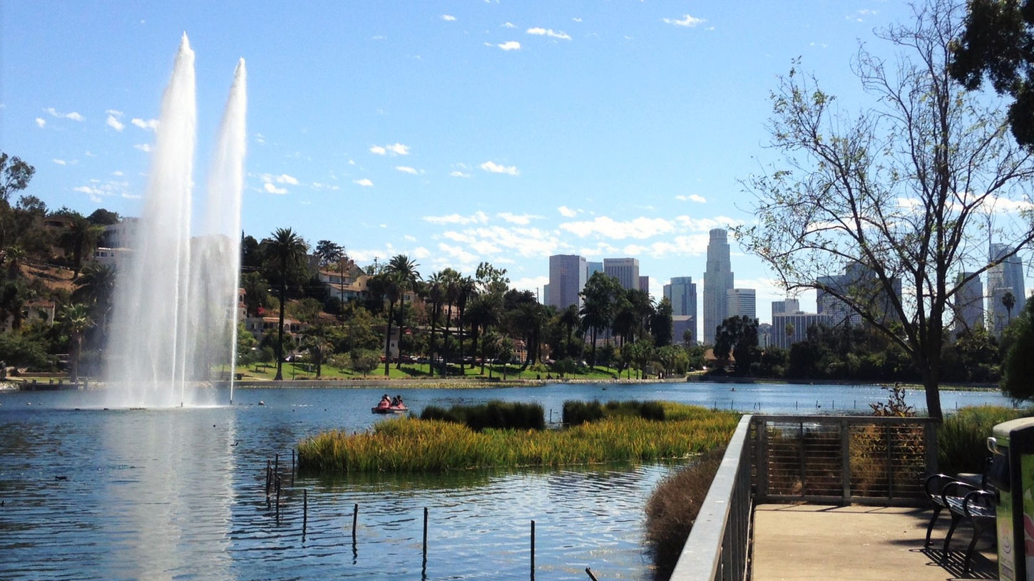 Scenic lake with pedal boats, lotus flowers, and skyline views of downtown LA.