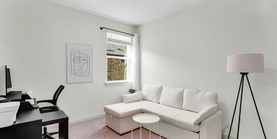 Bedroom with queen-size sofa bed and home office setup.