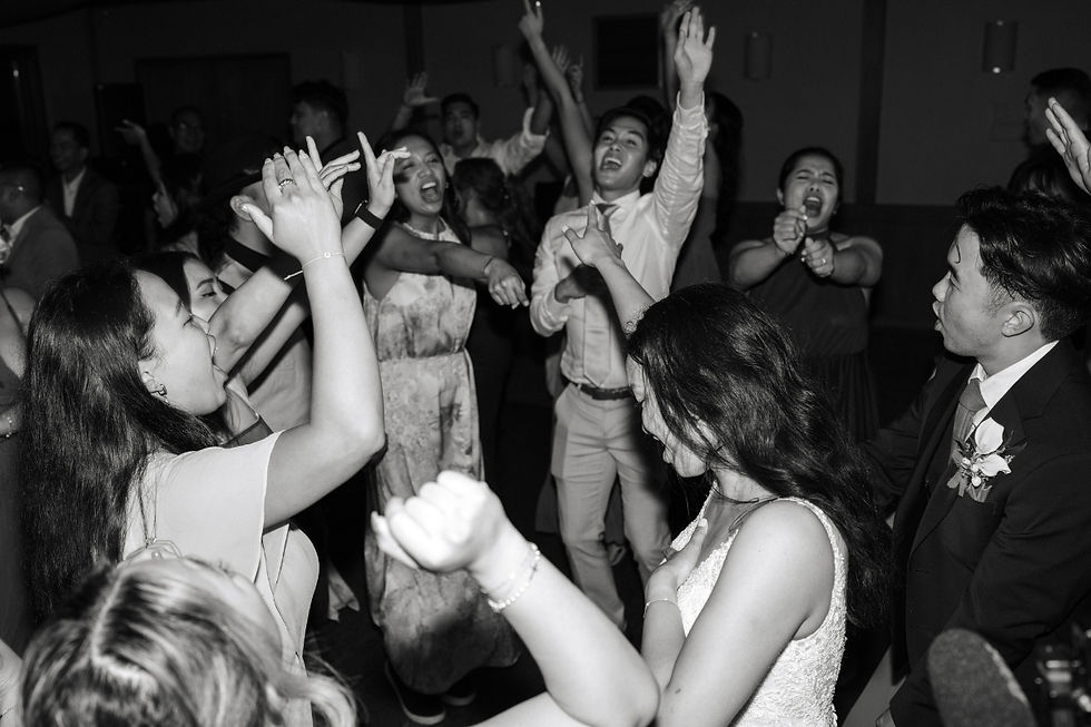 Wedding guests dancing and cheering on a crowded floor.