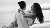 Man holding a laughing woman on a beach in black and white