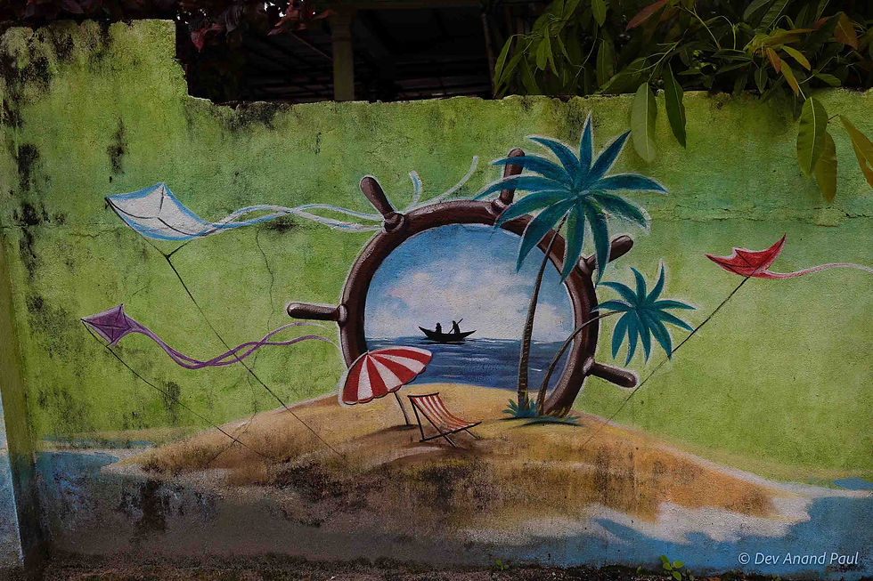 A tropical beach scene framed within a ship’s wheel—a boat with two fishermen sailing in the distance, swaying palms, kites flying, and a beach chair with an umbrella on a sandy shore