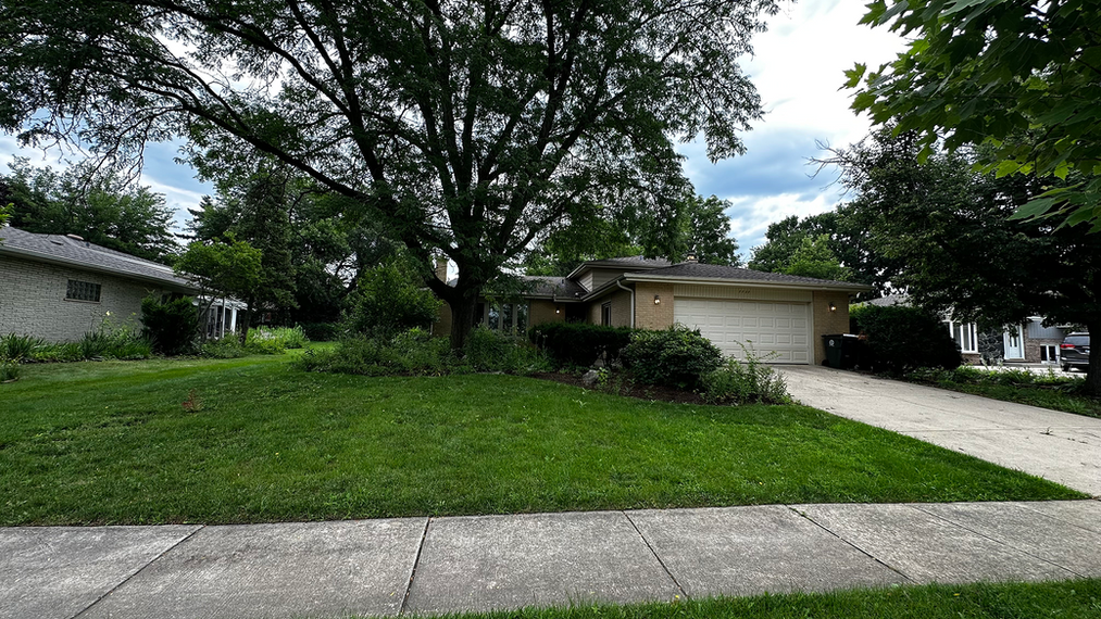 Front yard with manicured bushes and shrubs behind green freshly cut grass.