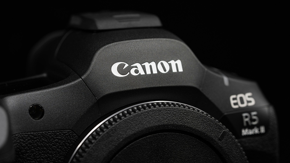 Close-up of a black Canon EOS R5 Mark II camera body on a dark background.