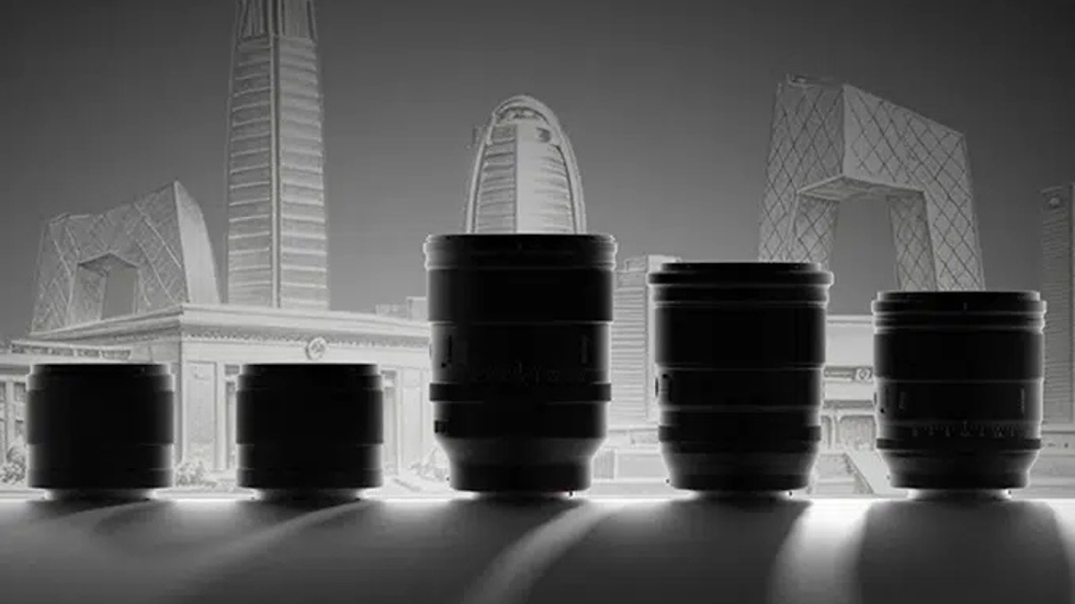 Five black camera lenses silhouetted on a table in front of a grayscale city skyline with modern skyscrapers