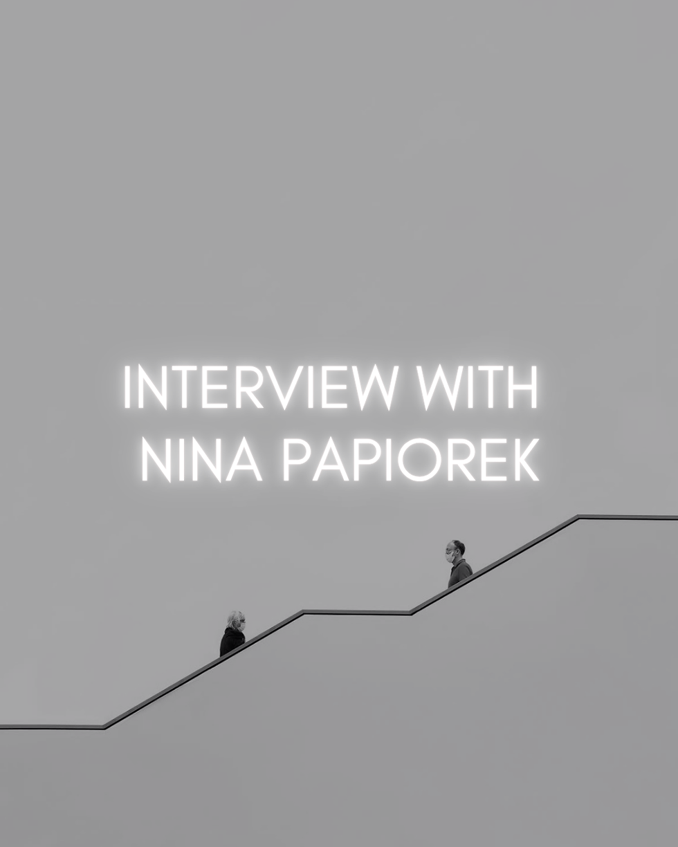 Interview with Nina Papiorek in glowing white text above two masked people on a minimalist gray staircase.
