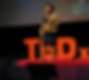 Dr Bentley-Edwards standing in front of a TEDxDuke sign.