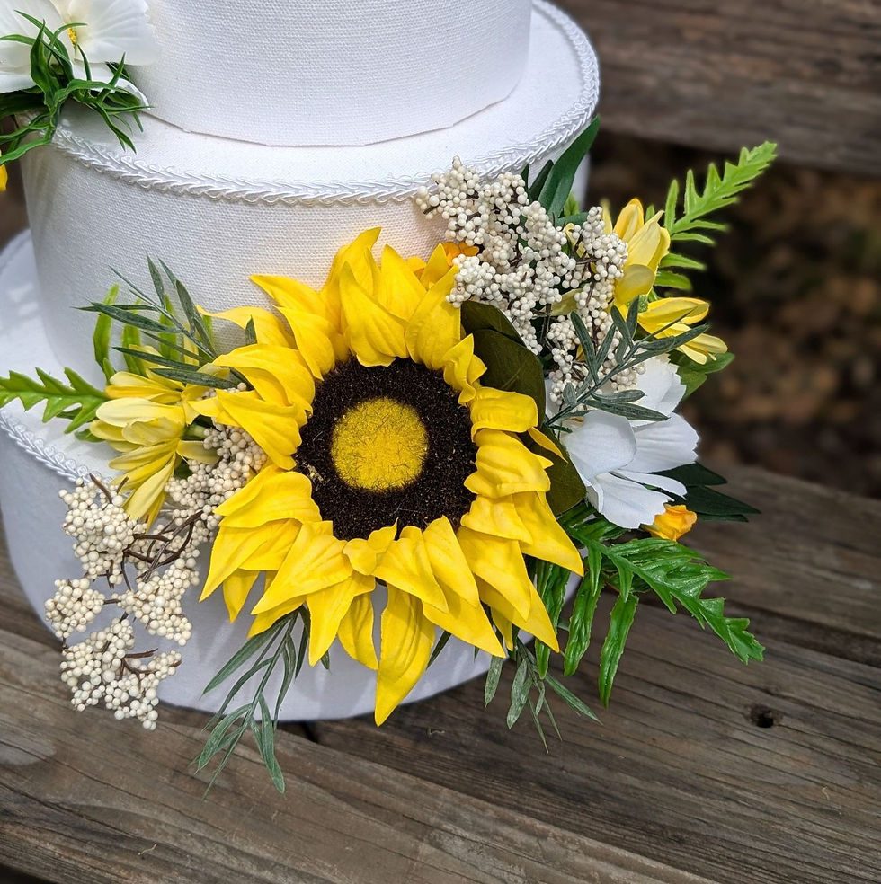 Sunlit Meadow sunflower cake flowers made with artificial yellow and white blooms.