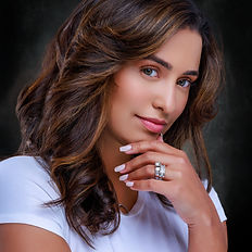 This image presents a professional portrait of a woman in a suit, exuding confidence with a friendly smile. The rich background adds depth to the image, enhancing her professional appearance. This type of photo is ideal for business contexts, personal branding, or professional networking.