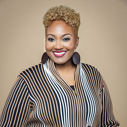 This image presents a professional portrait of a woman in a suit, exuding confidence with a friendly smile. The rich background adds depth to the image, enhancing her professional appearance. This type of photo is ideal for business contexts, personal branding, or professional networking.