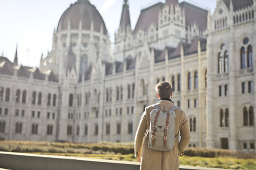 male-wearing-brown-coat-backpack-near-hungarian-parliament-building-budapest-hungary.jpg