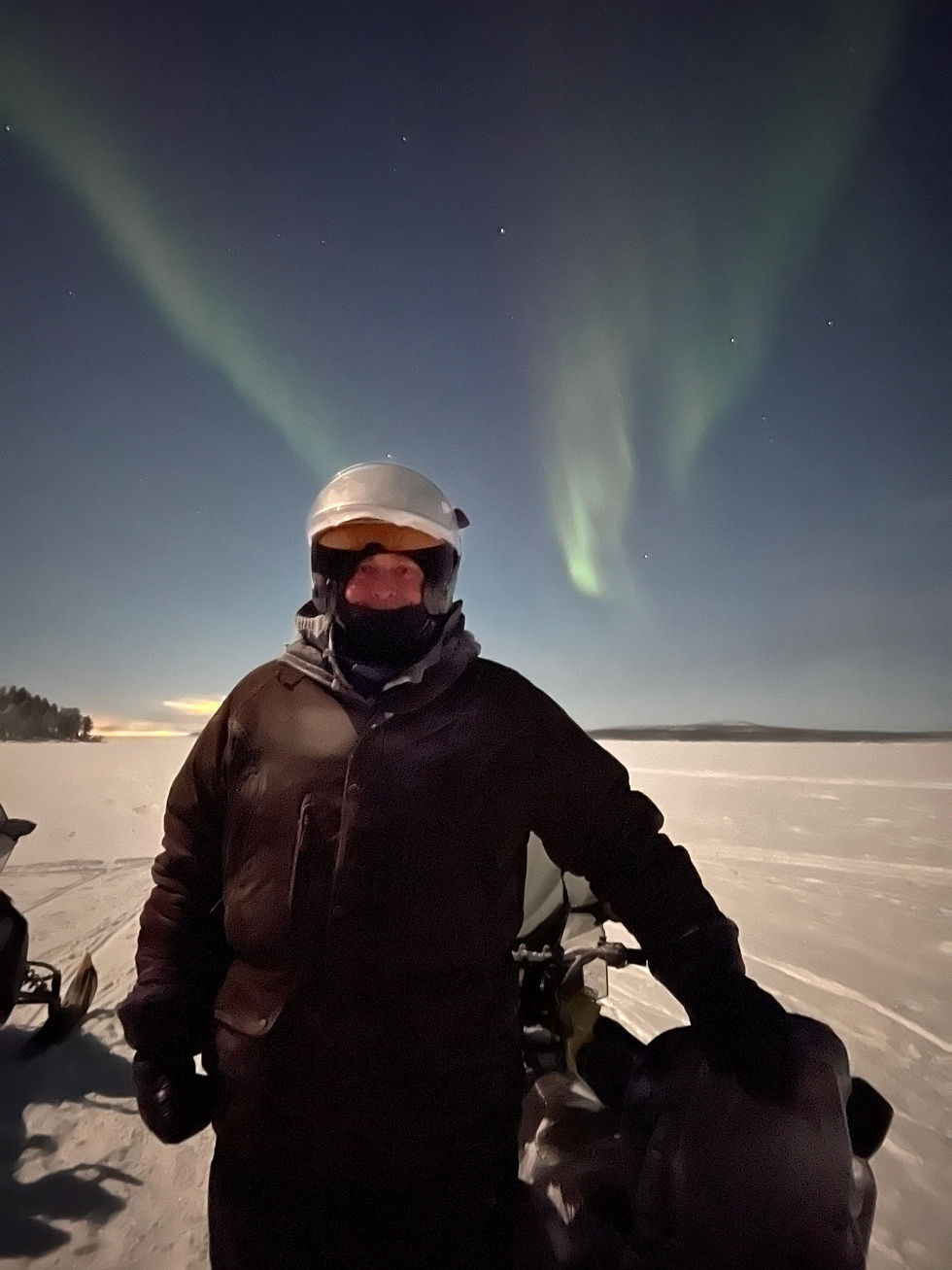 Travelling on a Skidoo over a frozen lake with the Aurora Borealis above, 
