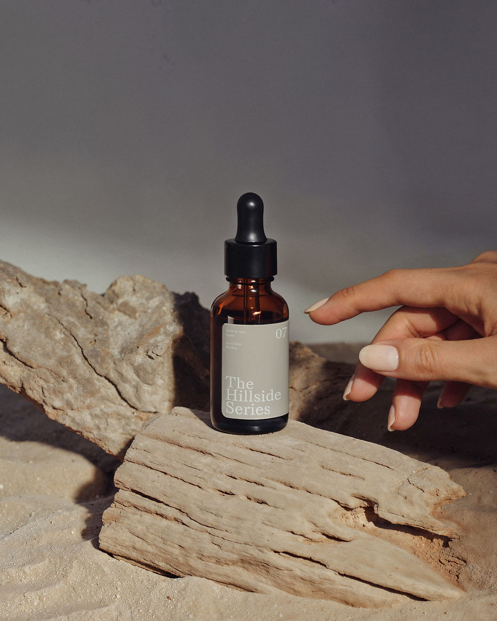 Amber glass dropper bottle standing on weathered wood with a woman's hand reaching towards it.
