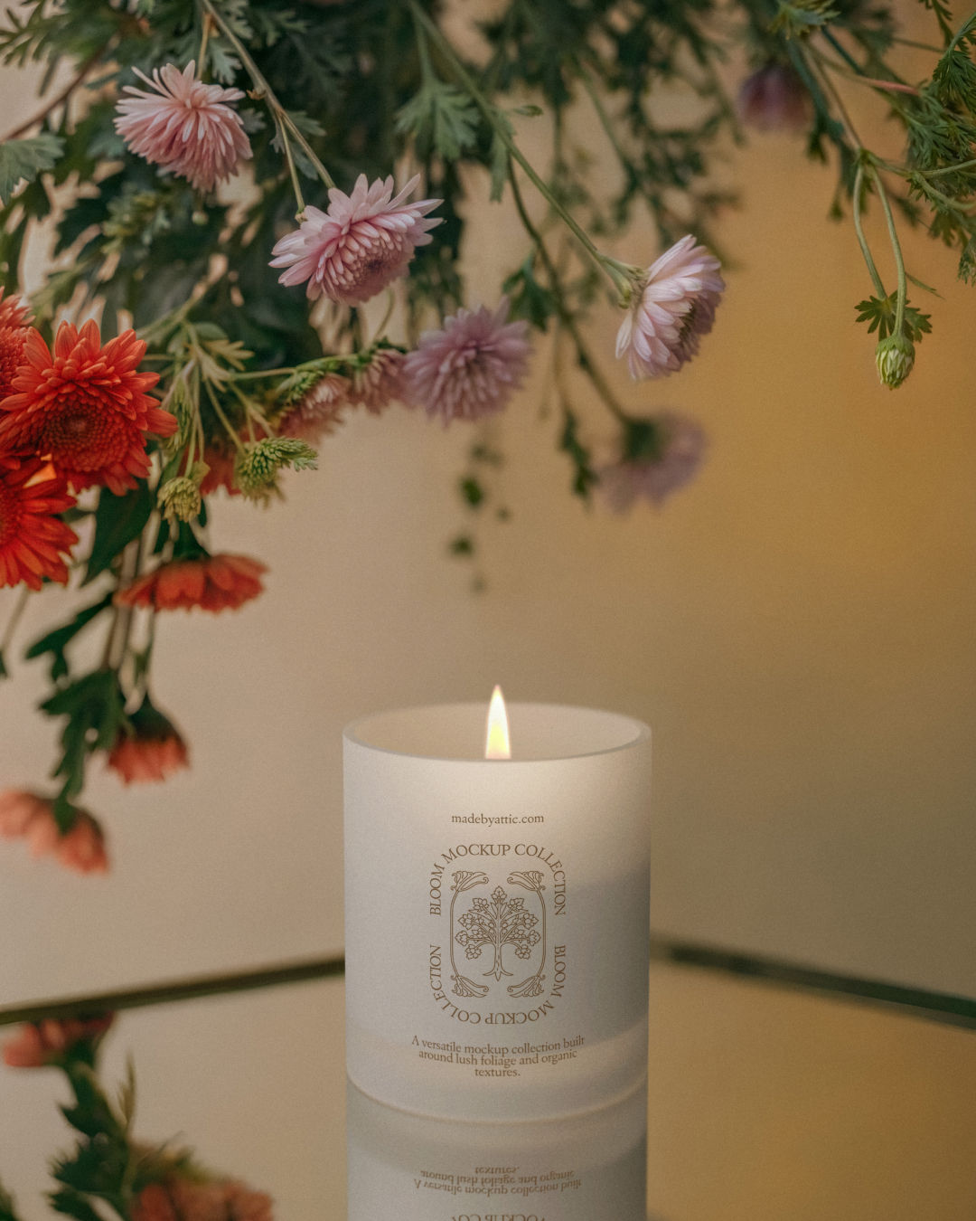 A high-fidelity frosted glass candle mockup with a lit flame on a mirrored surface under hanging pink and orange flowers.