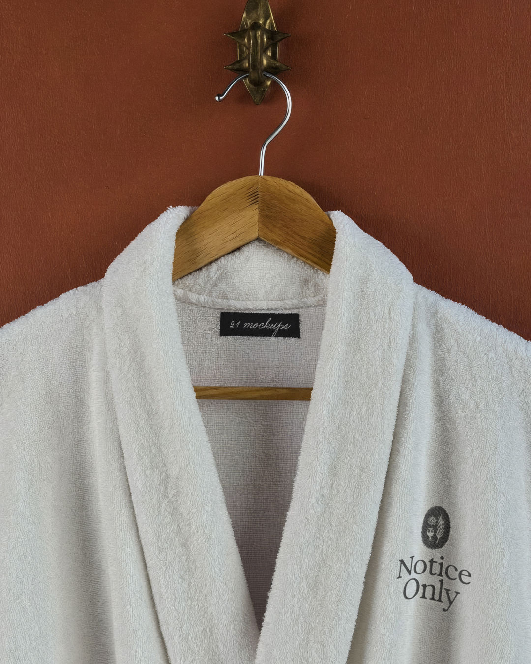 bath robe mockup, towelling robe on wooden hanger, brass hook, embroidered chest mark, espresso and blue walls, hotel brandin