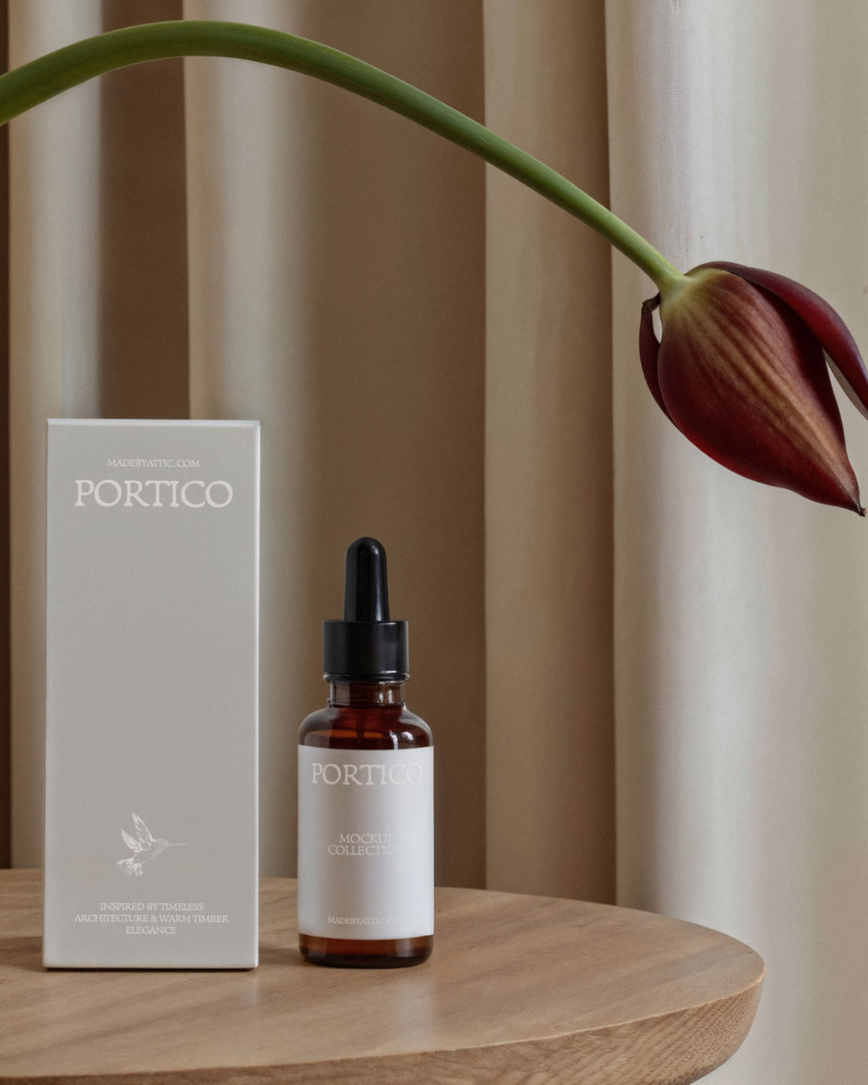 A high-fidelity dropper bottle and box mockup on a warm timber surface with a single tulip bowing over the scene.